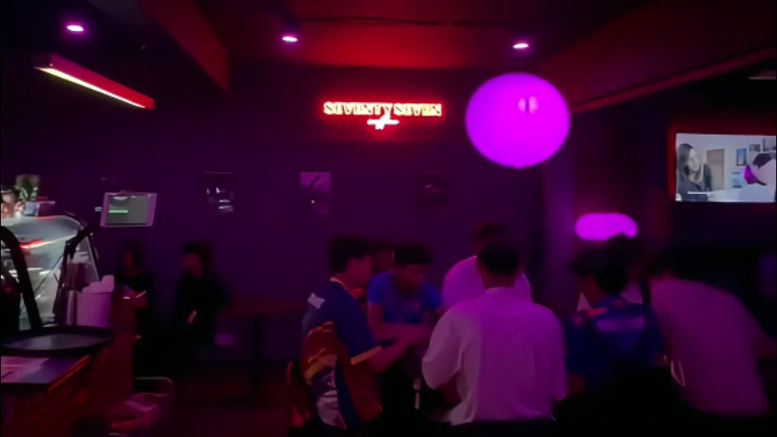 The Seventy7 Coffee room at night, with the neon sign glowing above a crowd